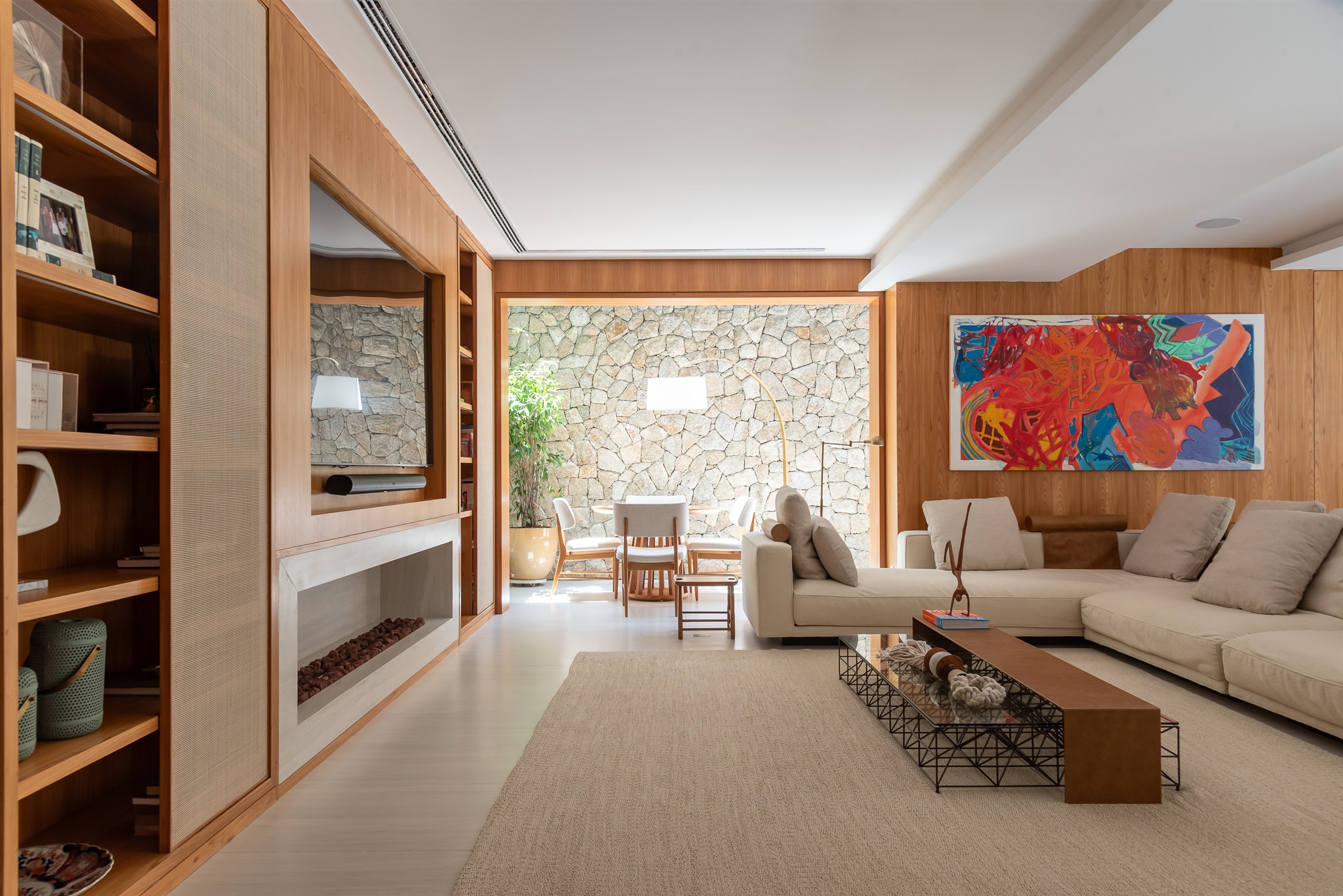 Sala com estante de madeira e parede de pedra